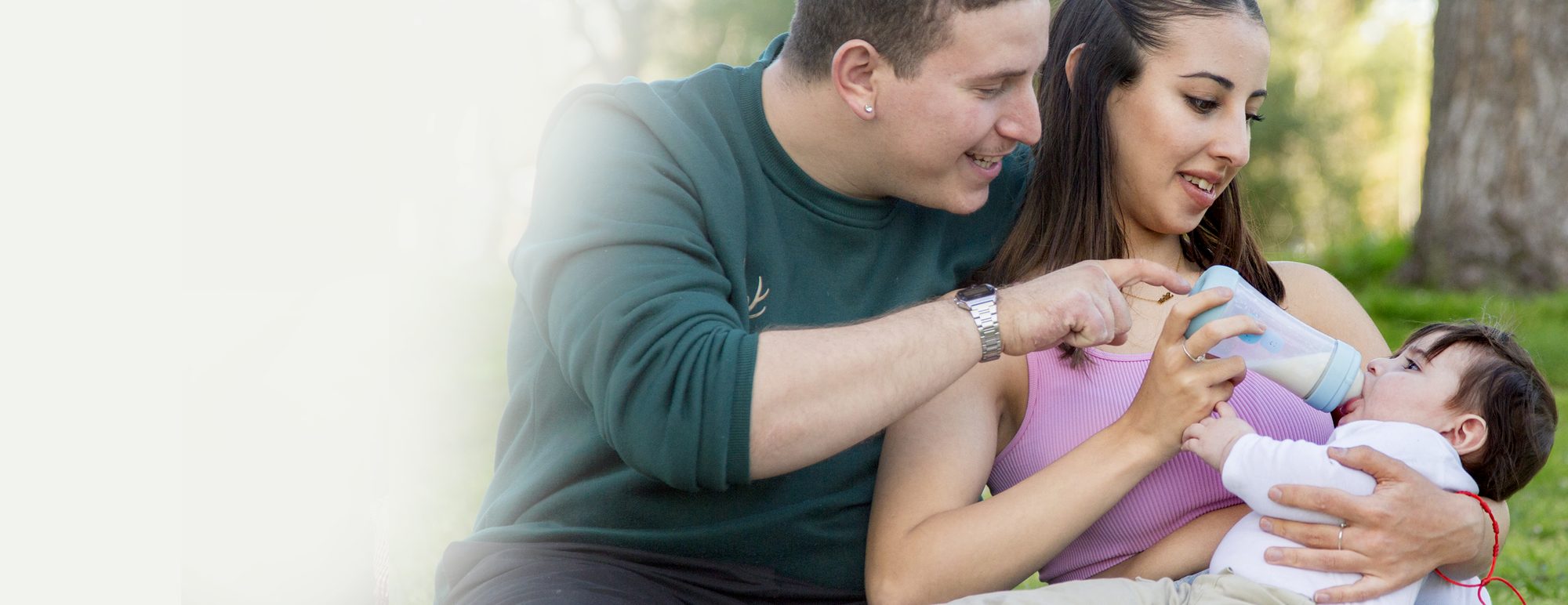 Parents feeding their baby a bottle in the park