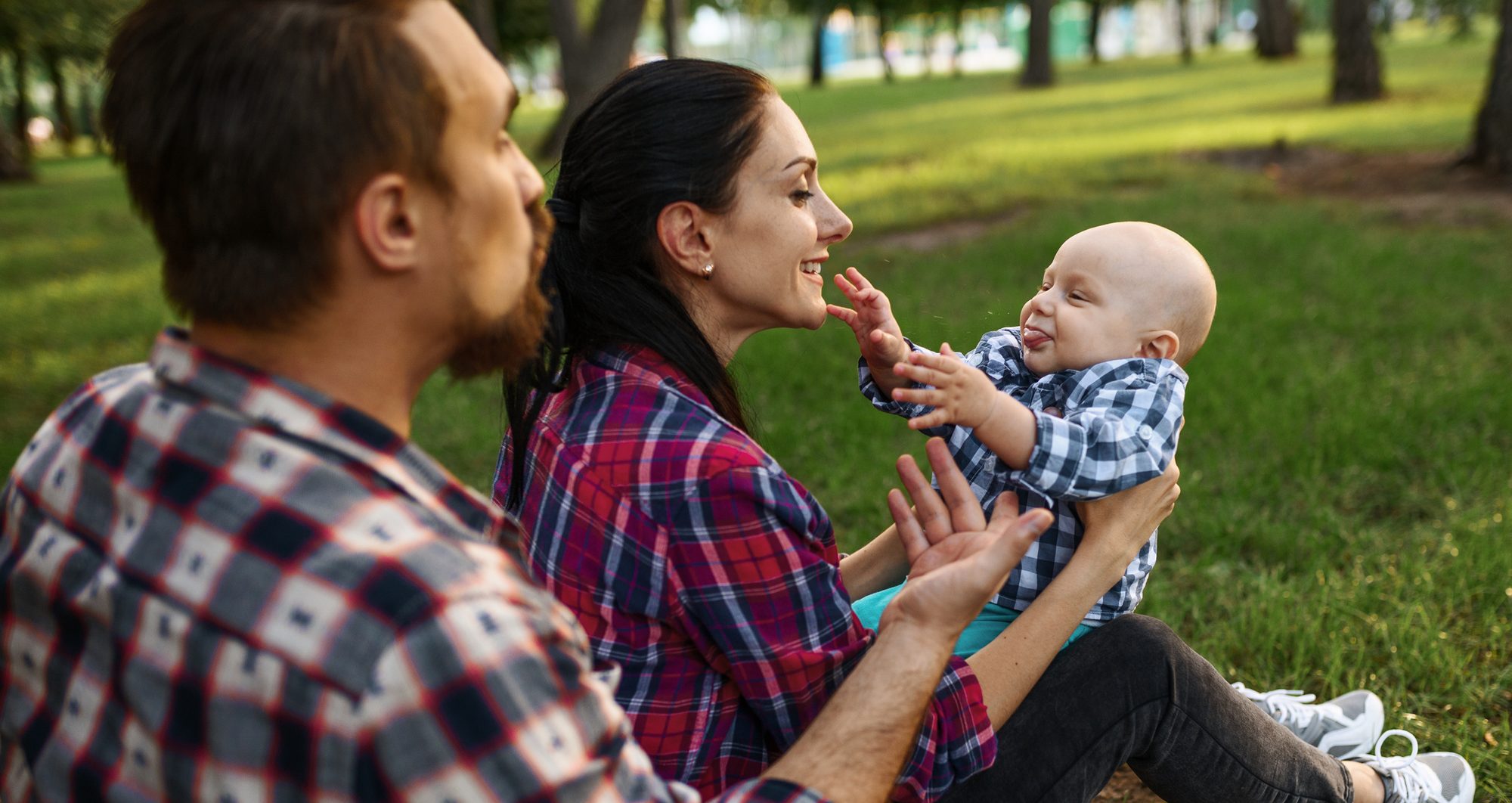 A mother and father playing with their baby on the grass