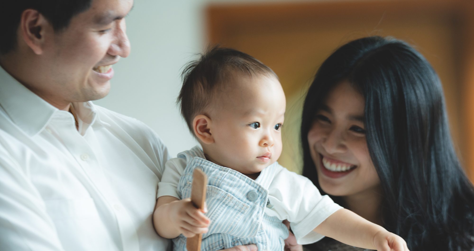 A family smiling with their baby by the window