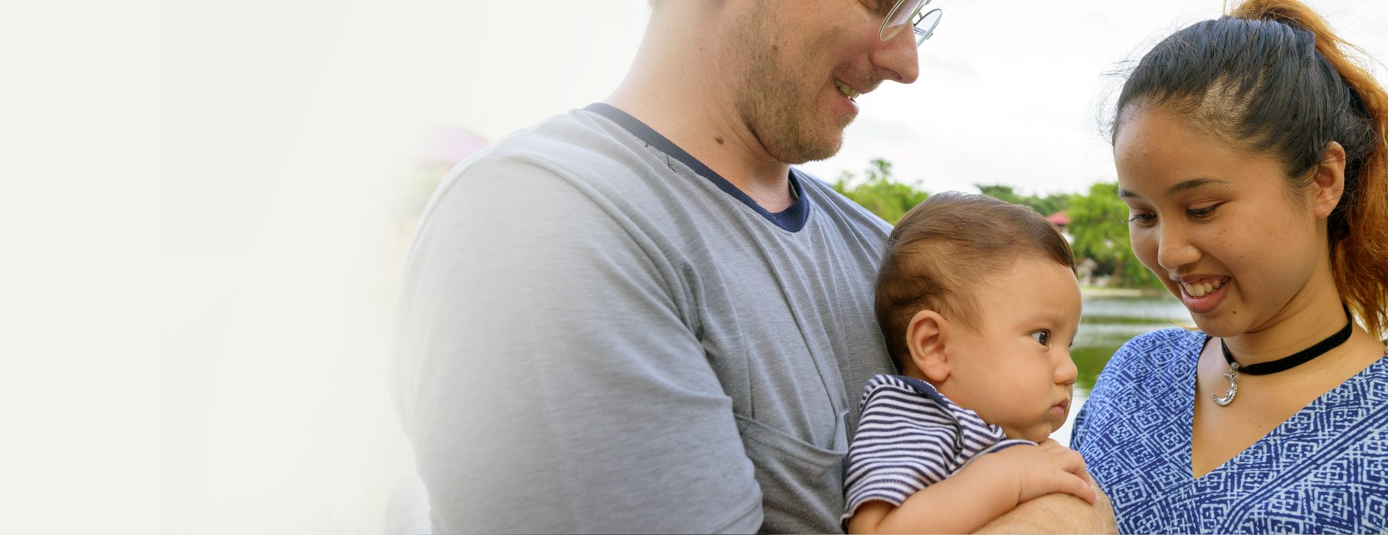 A couple holding their baby outdoors