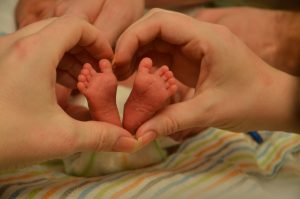 A newborn's feet held in a parent's hands